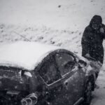 Weather Safety - a man standing next to a car covered in snow