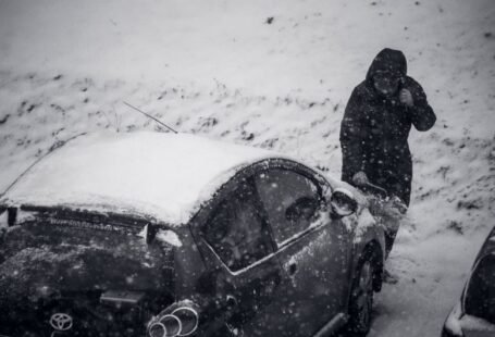 Weather Safety - a man standing next to a car covered in snow