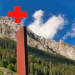 Tree First Aid - brown wooden cross on green grass field near mountain under blue and white cloudy sky during