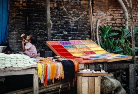 Cultural Practice - a woman sitting on a bench next to a colorful table