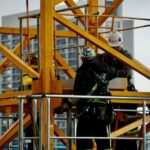 Safety Gear - man in black jacket and helmet climbing orange ladder