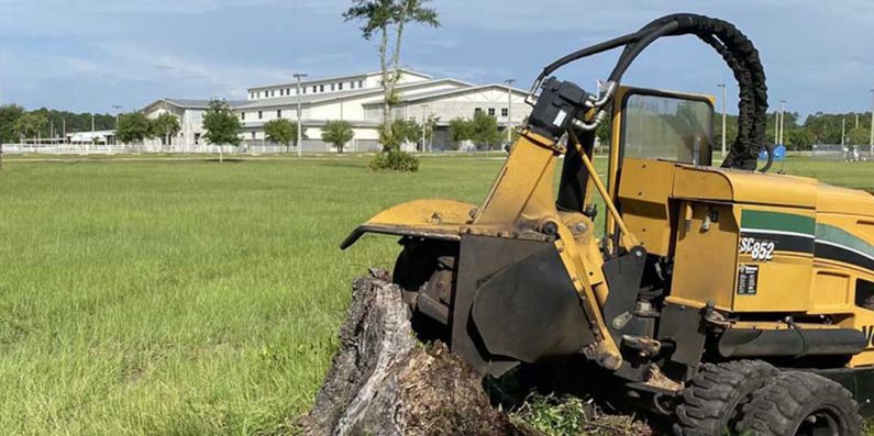 Stump Grinding - a tractor that is sitting in the grass